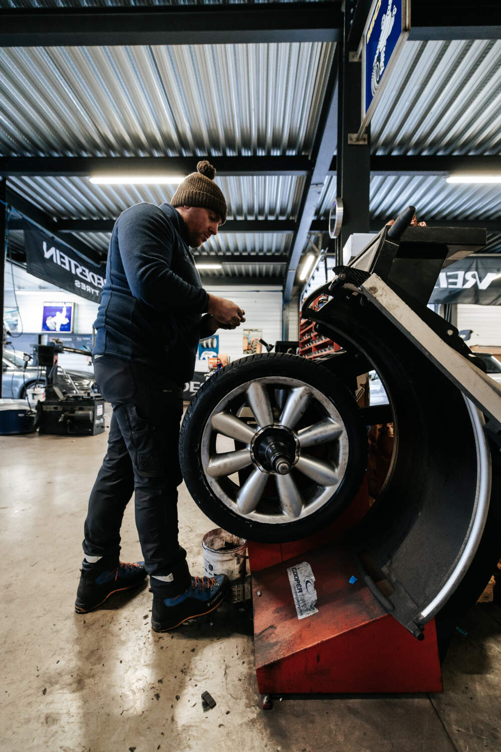 Photo d'un mécanicien entrain de réaliser le montage et l'équilibrage d'un pneu